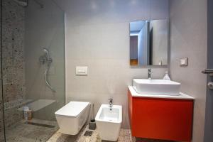 een badkamer met een wastafel, een toilet en een douche bij Blloku Unique Apartments in Tirana