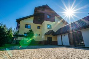 a house with the sun shining behind it at Przytulny Apartamencik- Willa Lawenda in Rytro