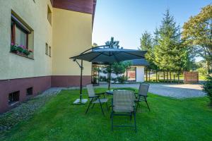 a table and chairs with an umbrella in the grass at Przytulny Apartamencik- Willa Lawenda in Rytro