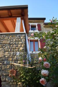 a house with a stone wall and flowers in front of it at Apartman CASA MARŠIĆ in Oprtalj