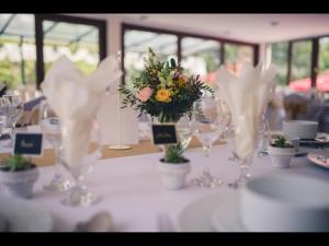 賴恩法盧的住宿－Admiralitás Kitchen and Restaurant，桌子上放着眼镜和一束鲜花