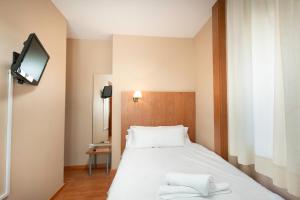 una camera da letto con un letto bianco e una televisione di RESIDENZA a Zamora