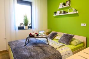 Un dormitorio verde con una cama con una mesa. en Apartmaji BANONIA " Poletni vetrc ", en Banovci