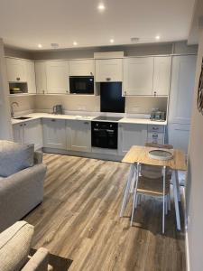 a kitchen with white cabinets and a table and a couch at THE ESK - Modern 1 bedroom apartment in centre of Melrose. in Melrose