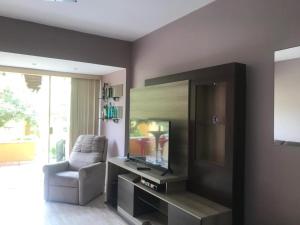 a living room with a television and a chair at Flat WinterVille Residence - Gravatá in Gravatá