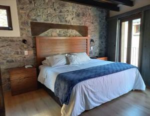 a bedroom with a large bed with a stone wall at Hotel Canaria in Santeagueda