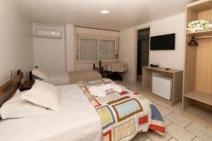 ein Hotelzimmer mit einem Bett und einem TV in der Unterkunft Hotel Igrejinha in Igrejinha
