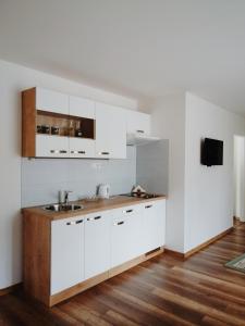 a kitchen with white cabinets and a wooden floor at Apartmán pri parku in Seredʼ