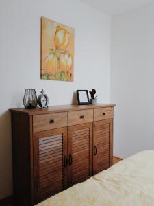 a wooden cabinet in a bedroom with a painting on the wall at Apartmán pri parku in Seredʼ