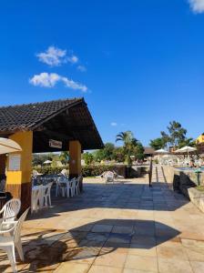 a patio with white chairs and tables and umbrellas at Flat WinterVille Residence - Gravatá in Gravatá