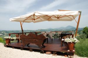 a wooden deck with an umbrella and tables and chairs at Casale Druida in Poggio Mirteto