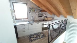 een keuken met witte kasten, een wastafel en een raam bij Casa Luna in Pieve di Cadore