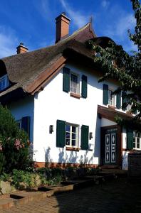 a white house with green shutters and a roof at Insel Landhaus Feuerstein in Gager