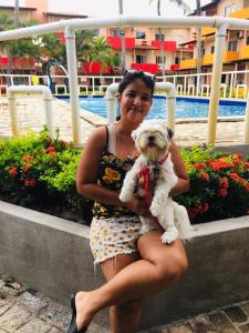 a woman is holding a small white dog at AP DA FABY in Barra de São Miguel