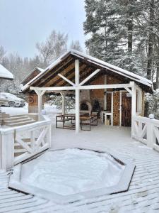 een paviljoen met een hot tub in de sneeuw bij Chalet Mlyn in Myhove