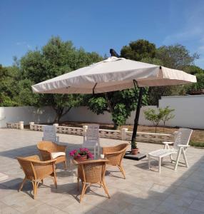 a table and chairs and an umbrella on a patio at Villa Cohiba - 700m dal mare in Pulsano