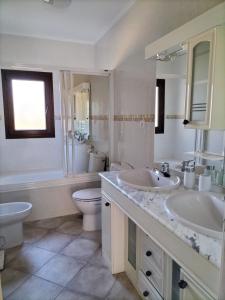 a white bathroom with two sinks and a toilet at Puerta Laguna - Casa con parcela in Hita