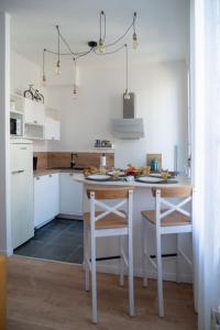 uma cozinha com armários brancos e uma mesa e cadeiras em Marseille Désirée - Centre - La Joliette - gare TGV em Marselha