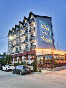 a hotel building with cars parked in a parking lot at Hotel Dragului in Predeal