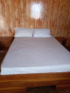 drewniane łóżko z białą pościelą i poduszkami w obiekcie Le Figuier w mieście Pointe-Saint-Georges