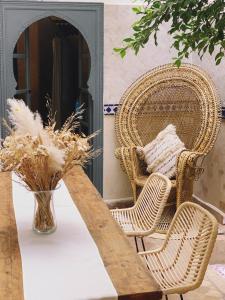 a table with two wicker chairs and a vase at Riad of The Light in Marrakesh