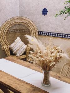 a vase of flowers on a table with a chair at Riad of The Light in Marrakesh