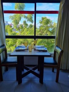 uma mesa e cadeiras num quarto com uma grande janela em Quarto 215 do Manos Royal Hotel - propriedade privada em João Pessoa