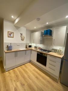 a kitchen with white cabinets and a stove top oven at The Cove in Criccieth