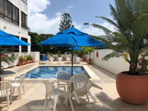 a pool with chairs and a table with a blue umbrella at Penthouse Bahía Fragata in San Andrés