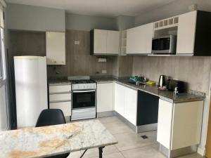 una cocina con electrodomésticos blancos y una mesa. en Dean Funes Suites 607 en Salta