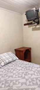 1 dormitorio con 1 cama y TV en la pared en Pousada Recanto Do sagui, en Morretes