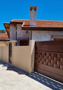 a house with a fence and a garage at Chalés Bella in Monte Verde