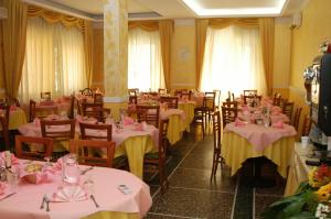 uma sala com mesas e cadeiras com toalhas de mesa rosa e amarela em Hotel Giannella em Rimini