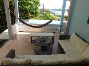 een woonkamer met een bank en een hangmat op een balkon bij Villa KANEPICE in La Trinité
