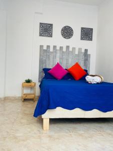 a bedroom with a blue bed with colorful pillows at Kumbianna in Cartagena de Indias