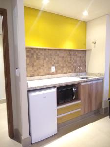 eine Küche mit einer Spüle und einer Mikrowelle in der Unterkunft Grein Solar das Águas Park Resort in Olímpia