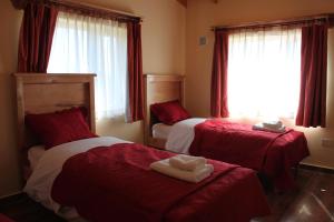 a bedroom with two beds with red and white sheets at Eco Vista Hotel in El Calafate