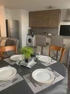 a table with plates and silverware on it in a kitchen at Grand appartement proche de Paris in Chilly-Mazarin