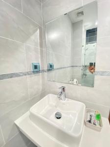 Baño blanco con lavabo y espejo en Liên’s Mini Hotel, en Phu Quoc