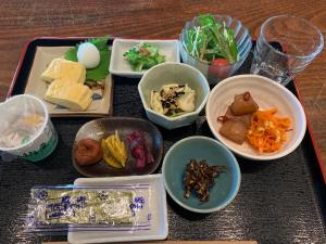 ein Tablett mit Schüsseln Essen auf einem Tisch in der Unterkunft ペンションニライカナイ in Awaren