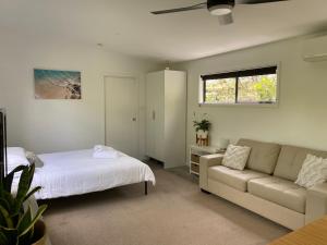 a bedroom with a bed and a couch and a window at Bali In Berrara in Berrara