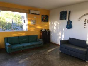 una sala de estar con 2 sofás y una guitarra en la pared en La Ventolina, en Puerto Pirámides
