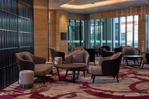 Opero Hotel Southkey Johor Bahru في جوهور باهرو: غرفة انتظار مع كراسي وطاولات ونوافذ