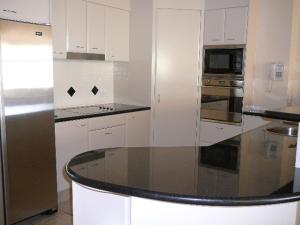 a kitchen with white cabinets and a glass counter top at Magnolia Lane Apartments in Twin Waters