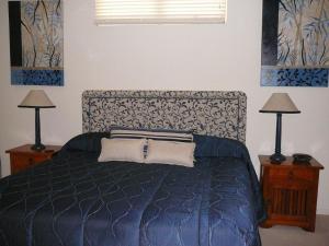 a bedroom with a blue bed with two lamps at Magnolia Lane Apartments in Twin Waters