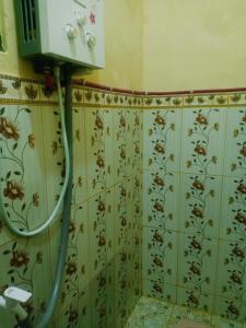 een badkamer met bloemenbehang aan de muur bij Full house Aqiela syariah in Wonosobo
