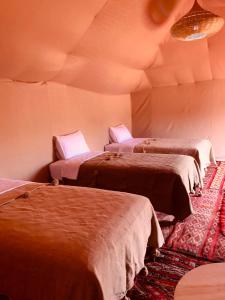 eine Gruppe von 3 Betten in einem Zimmer in der Unterkunft Travel Oasis Merzouga Camp in Merzouga