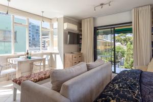 a living room with a couch and a dining room at Cosy and Classy Sea Point Apartment in Cape Town