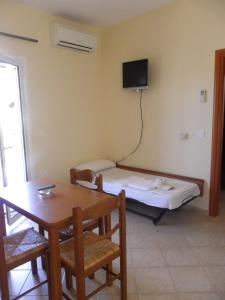 um quarto com uma cama, uma mesa e uma televisão em Hotel Sea em Erateini