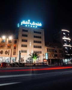 a building with a sign on top of it at night at Aghnar Hotel in An Najaf
